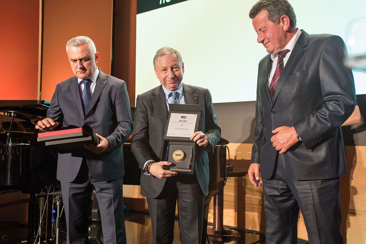 Predsjednik FIA-e g. Jean Todt pokazuje uručeno priznanje HAK-a FIA-i, uz njega predsjednik HAK-a Slavko Tušek (na slici desno) i zamjenik predsjednika HAK-a Ivo Bikić (na slici lijevo)